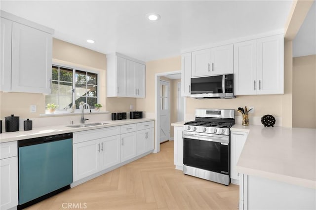 kitchen featuring sink, white cabinetry, appliances with stainless steel finishes, and light parquet floors