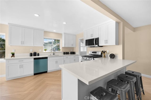 kitchen featuring light parquet flooring, white cabinetry, stainless steel appliances, kitchen peninsula, and a breakfast bar area