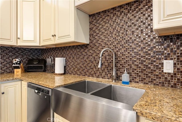 kitchen with light stone countertops, sink, backsplash, and stainless steel dishwasher