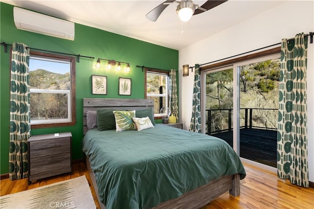 bedroom with ceiling fan, access to exterior, wood-type flooring, and an AC wall unit