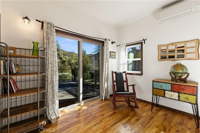 sitting room featuring wood-type flooring and a wall mounted air conditioner