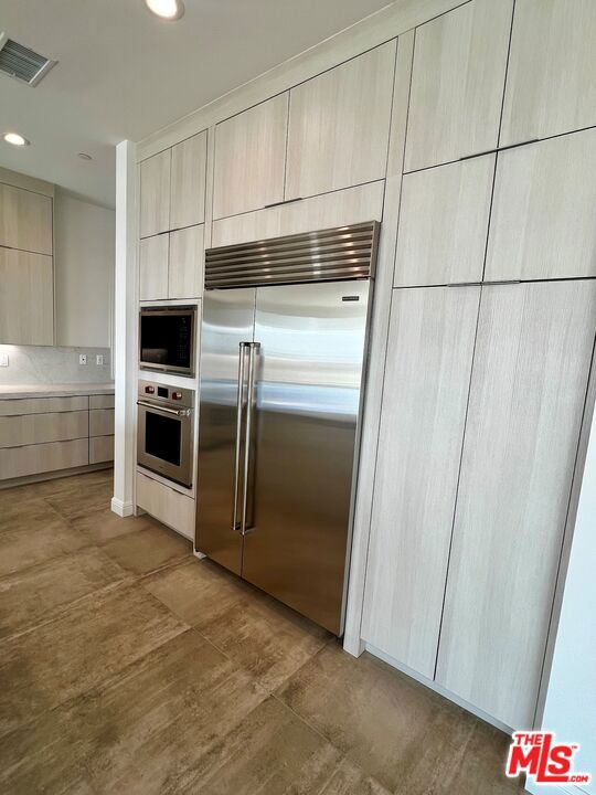 kitchen featuring built in appliances and light brown cabinets