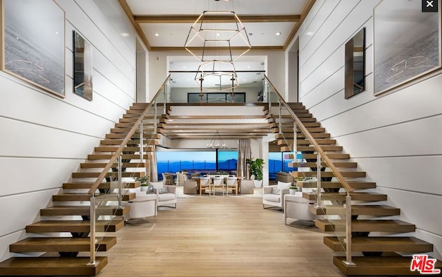 stairway featuring a notable chandelier, a towering ceiling, and wood-type flooring