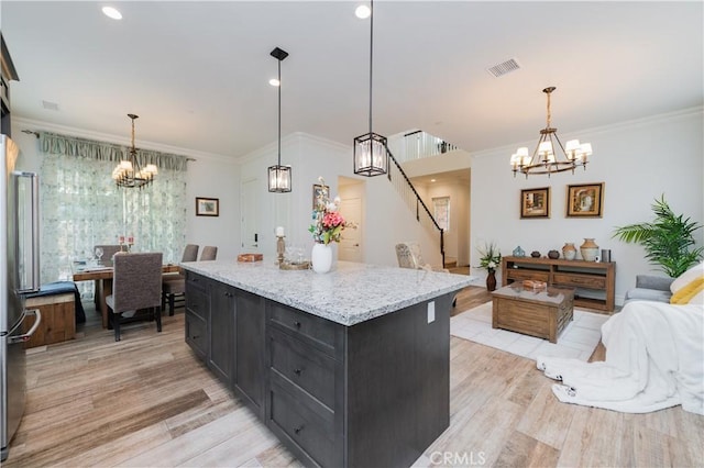 kitchen with stainless steel fridge, hanging light fixtures, crown molding, light hardwood / wood-style flooring, and a center island