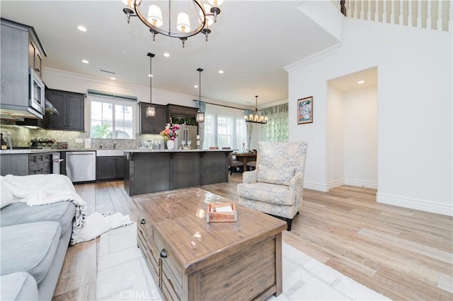 living room with light hardwood / wood-style floors, ornamental molding, and a notable chandelier