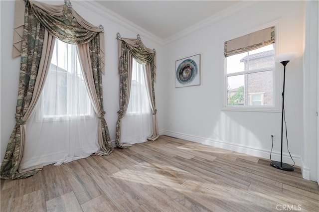 spare room featuring a healthy amount of sunlight, crown molding, and light hardwood / wood-style flooring