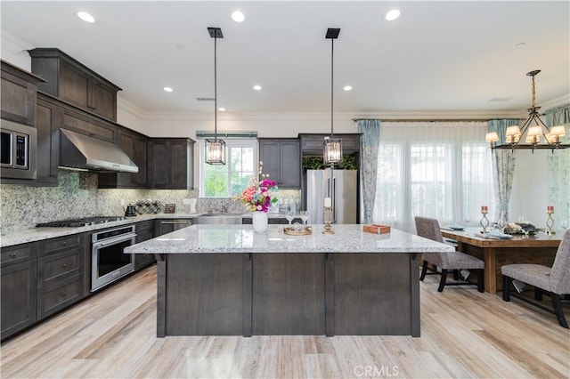 kitchen with decorative light fixtures, ventilation hood, stainless steel appliances, and a center island