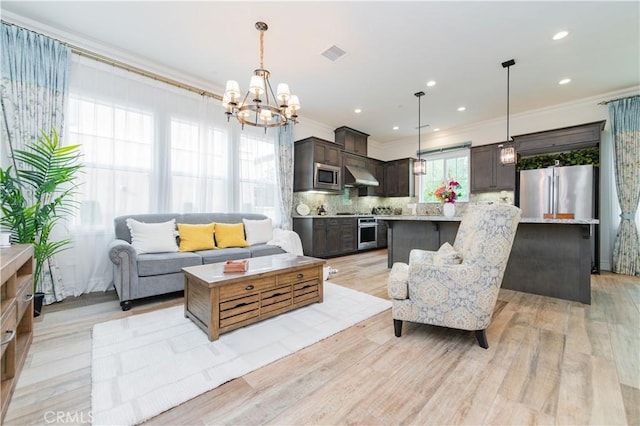 living room with crown molding, a chandelier, and light wood-type flooring