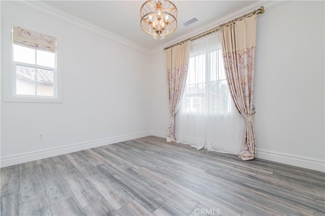 empty room with hardwood / wood-style flooring, crown molding, and an inviting chandelier