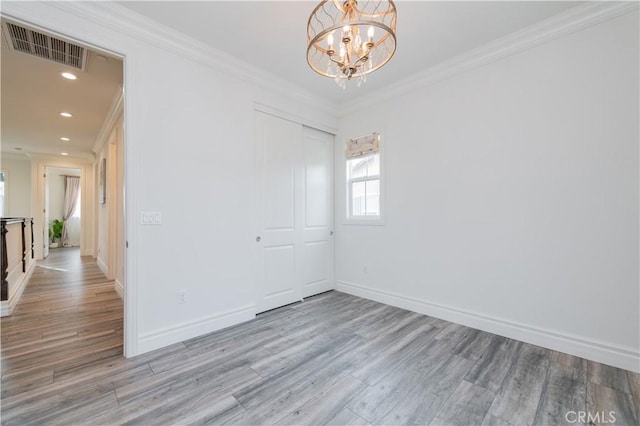 empty room featuring an inviting chandelier, ornamental molding, and light hardwood / wood-style floors