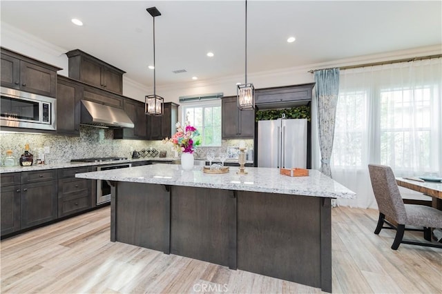 kitchen with extractor fan, a kitchen island, crown molding, hanging light fixtures, and appliances with stainless steel finishes