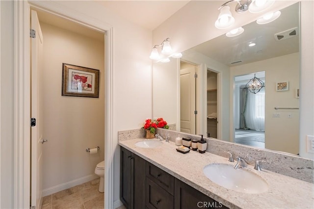 bathroom featuring toilet, vanity, and a notable chandelier