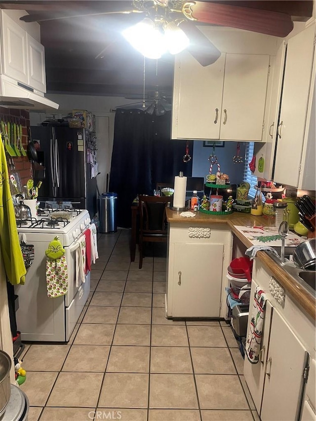 kitchen featuring white cabinets, gas range gas stove, black refrigerator, light tile patterned flooring, and ceiling fan