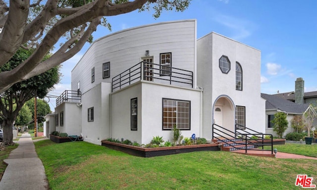 view of front of home with a front yard and a balcony