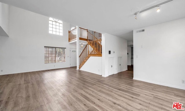 unfurnished living room with rail lighting and wood-type flooring