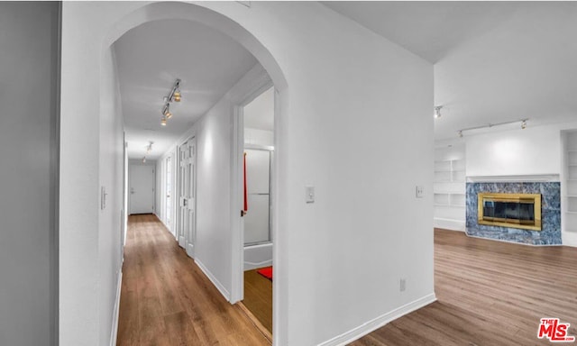 corridor with rail lighting and hardwood / wood-style flooring