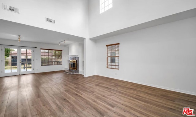 unfurnished living room with hardwood / wood-style flooring, a high ceiling, and french doors