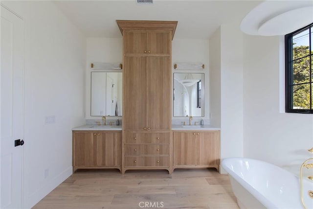 bathroom with a washtub, wood-type flooring, and vanity