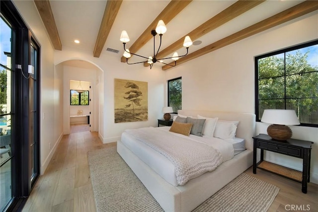 bedroom featuring ensuite bath, beamed ceiling, a chandelier, and light hardwood / wood-style flooring