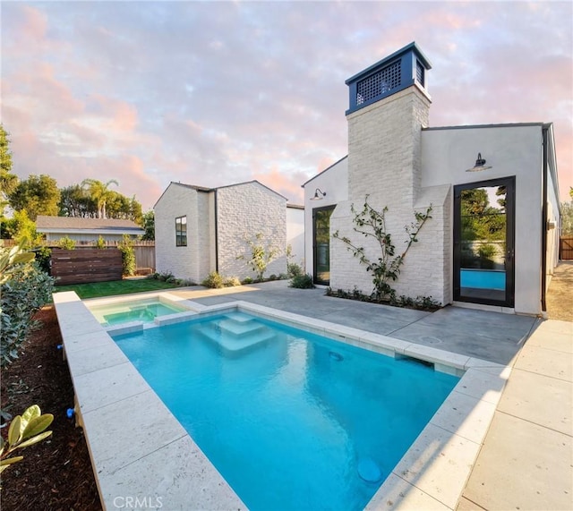 pool at dusk featuring a patio