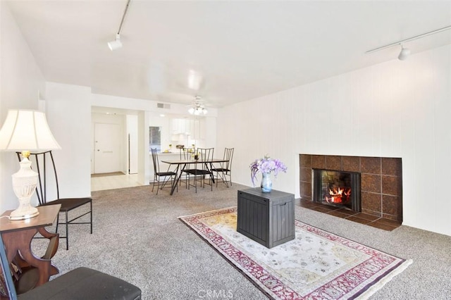 carpeted living room with ceiling fan, a fireplace, and rail lighting