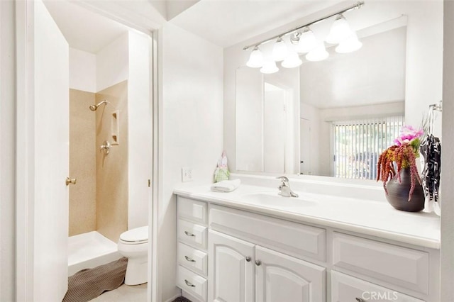 bathroom featuring a tile shower, vanity, and toilet