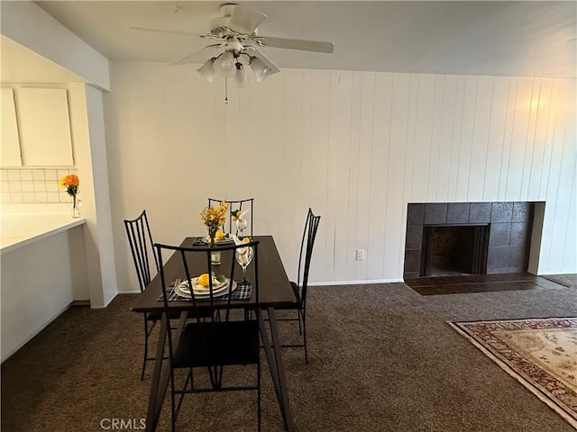 carpeted dining area with a fireplace and ceiling fan