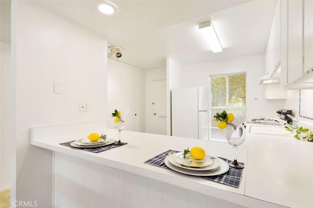 kitchen featuring white refrigerator, white cabinetry, and sink