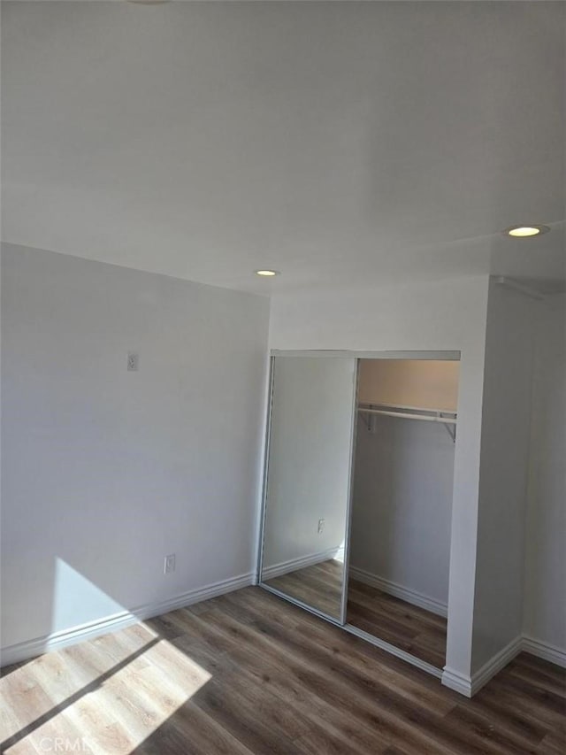 unfurnished bedroom with dark wood-type flooring and a closet