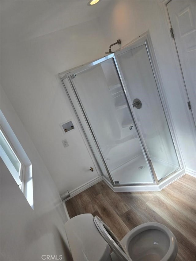 bathroom featuring an enclosed shower, wood-type flooring, and toilet