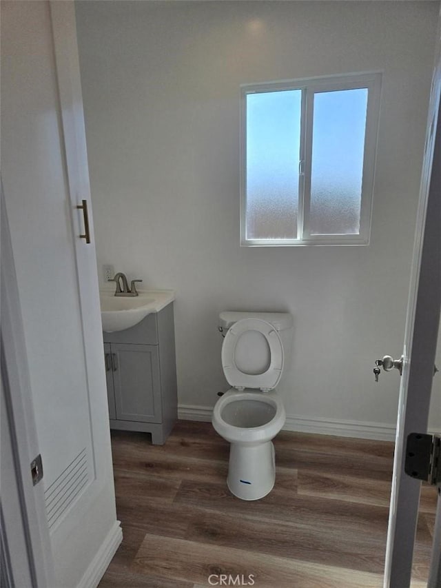 bathroom featuring toilet, hardwood / wood-style flooring, and vanity