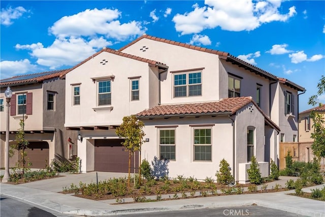 mediterranean / spanish-style house featuring concrete driveway, an attached garage, a tiled roof, and stucco siding