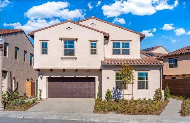 mediterranean / spanish home featuring a garage, fence, concrete driveway, a tiled roof, and stucco siding