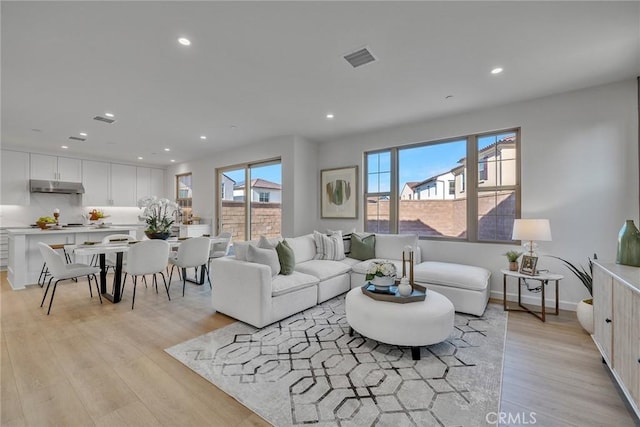 living room featuring baseboards, light wood-style flooring, visible vents, and recessed lighting