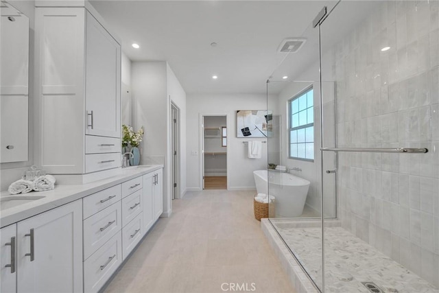 full bathroom with double vanity, visible vents, a freestanding bath, a sink, and a shower stall