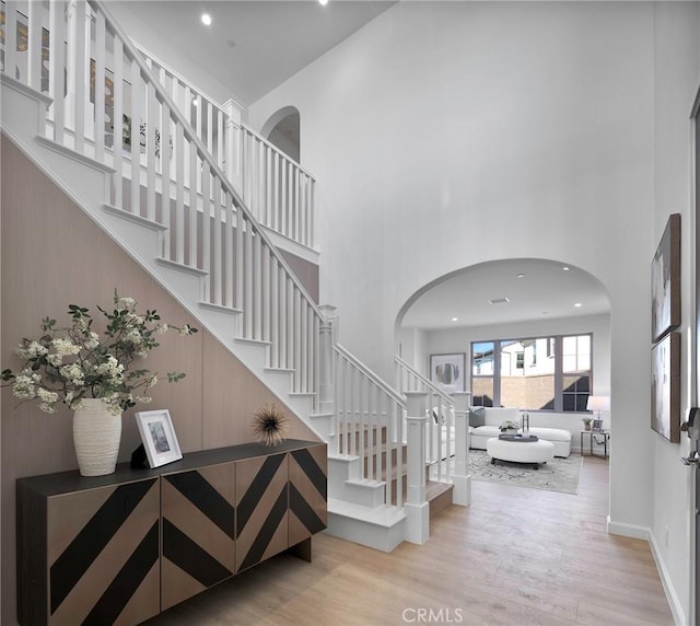 entrance foyer featuring baseboards, stairway, wood finished floors, a high ceiling, and recessed lighting