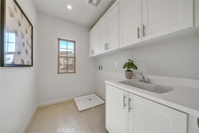 washroom featuring light tile patterned floors, hookup for a washing machine, cabinet space, a sink, and baseboards