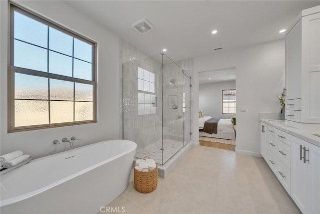 ensuite bathroom with connected bathroom, a freestanding tub, recessed lighting, vanity, and a stall shower