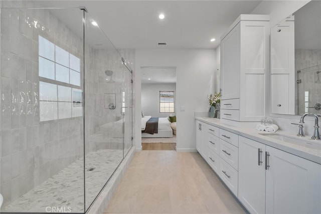 full bathroom with visible vents, a sink, a shower stall, and double vanity