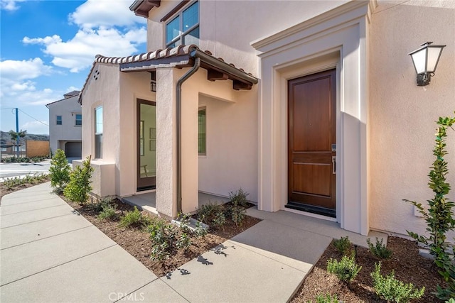 doorway to property with a tile roof and stucco siding