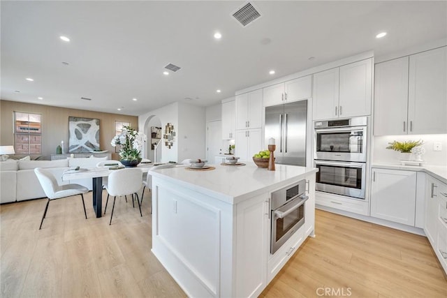 kitchen featuring white cabinetry, visible vents, appliances with stainless steel finishes, and arched walkways