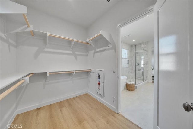 spacious closet featuring heating unit and light wood-style floors