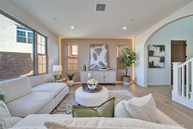 living area with arched walkways, recessed lighting, wood finished floors, visible vents, and baseboards