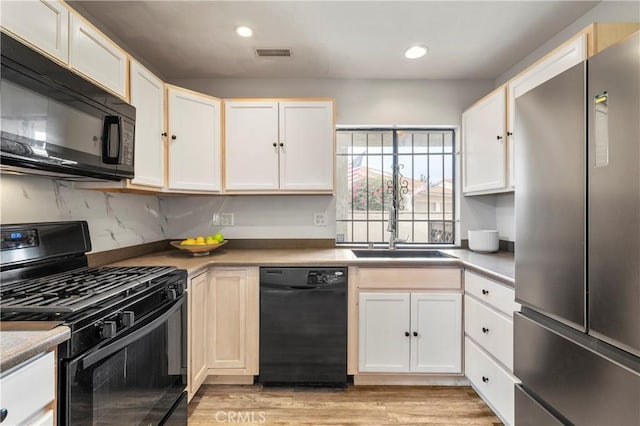 kitchen featuring light hardwood / wood-style flooring, white cabinets, backsplash, and black appliances