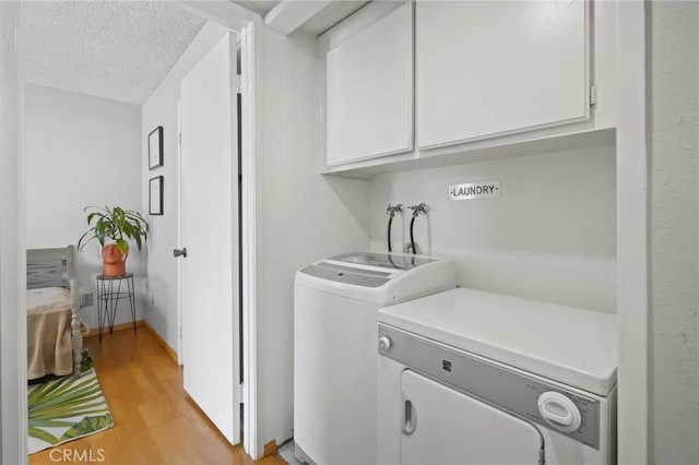 laundry area with cabinets, a textured ceiling, separate washer and dryer, and light hardwood / wood-style floors