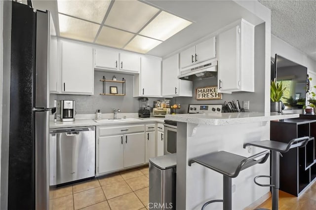 kitchen with kitchen peninsula, white cabinetry, sink, and stainless steel appliances