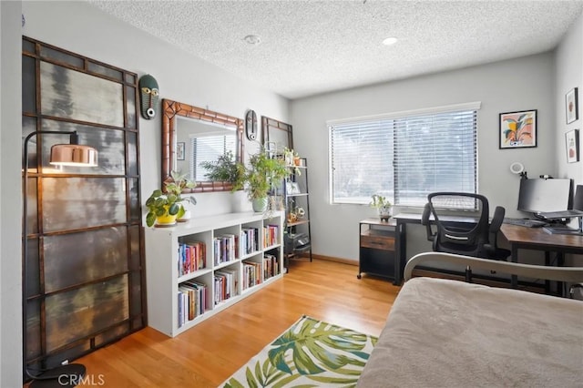 bedroom with a textured ceiling and light hardwood / wood-style flooring