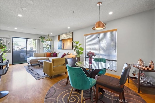 dining room with a healthy amount of sunlight, light wood-type flooring, and a textured ceiling