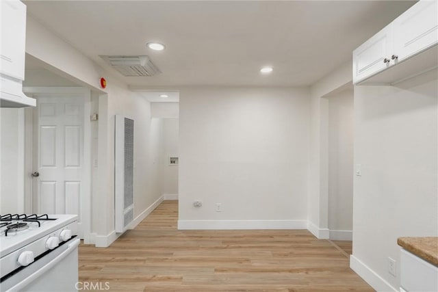 interior space with light hardwood / wood-style floors, white range, and white cabinetry