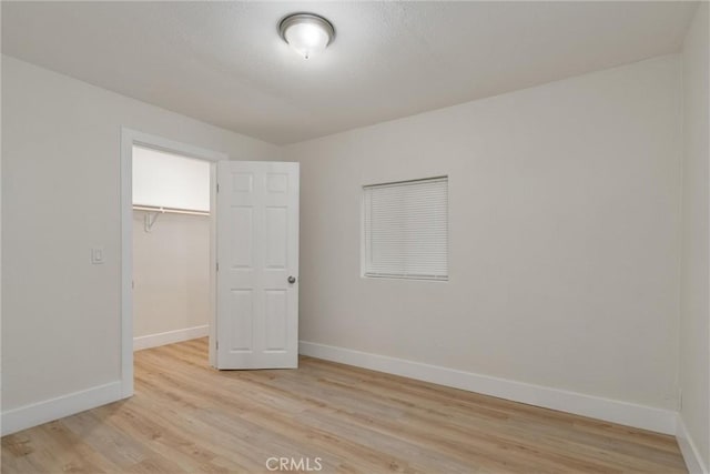 unfurnished bedroom featuring a walk in closet, light hardwood / wood-style flooring, and a closet